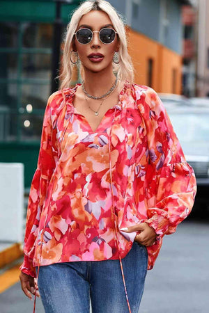 a woman in a floral blouse and jeans is walking down the street