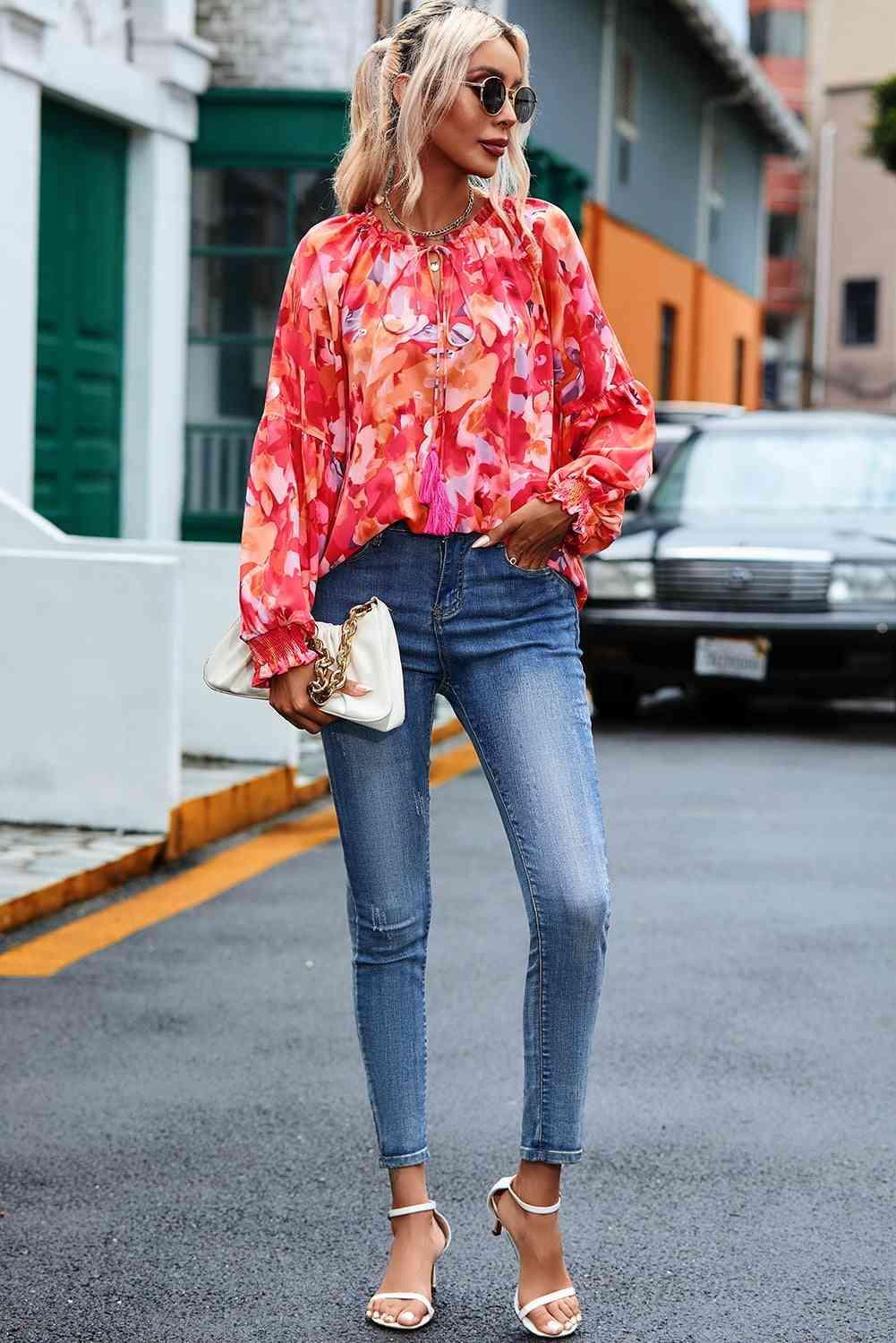 a woman standing on the street wearing jeans and a blouse