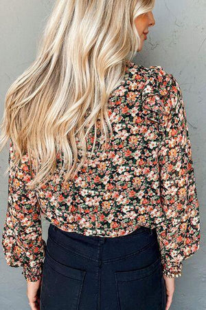 a woman with blonde hair wearing a floral blouse