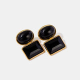 a pair of black and gold earrings on a white background