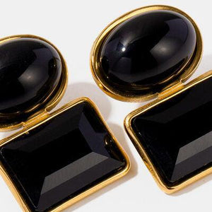 a pair of black and gold earrings on a white surface