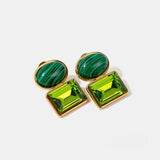 a pair of green and gold earrings on a white background