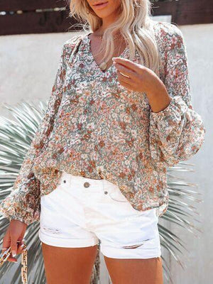 a woman wearing white shorts and a floral blouse