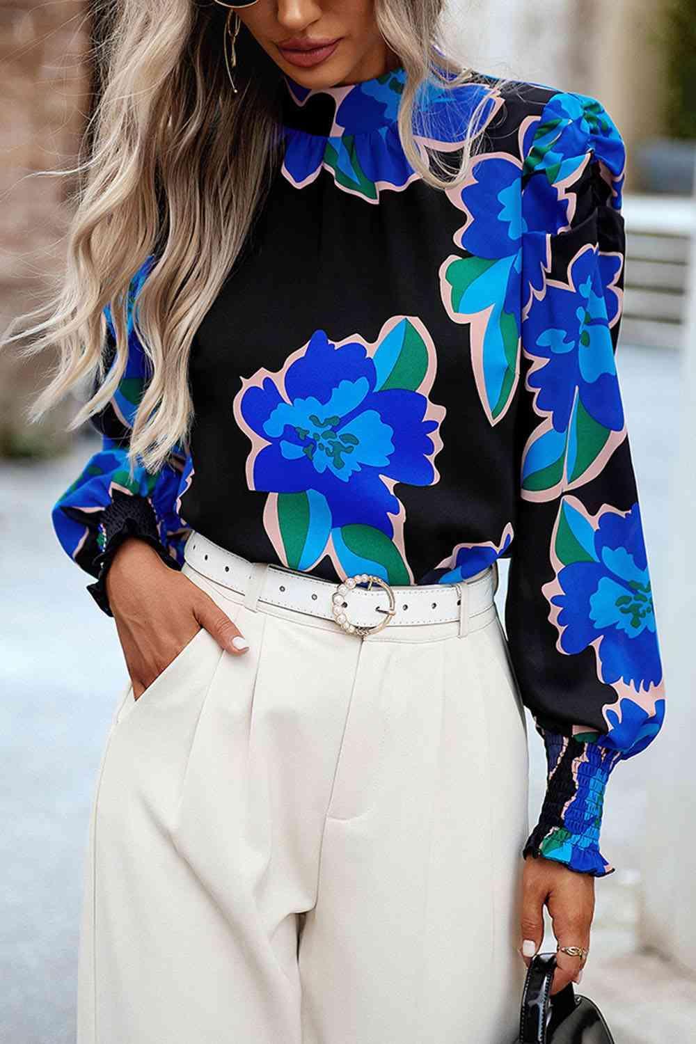 a woman wearing white pants and a blue floral blouse