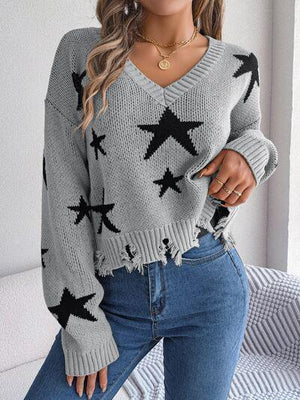 a woman wearing a grey sweater with black stars on it