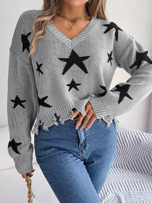 a woman wearing a grey sweater with black stars on it