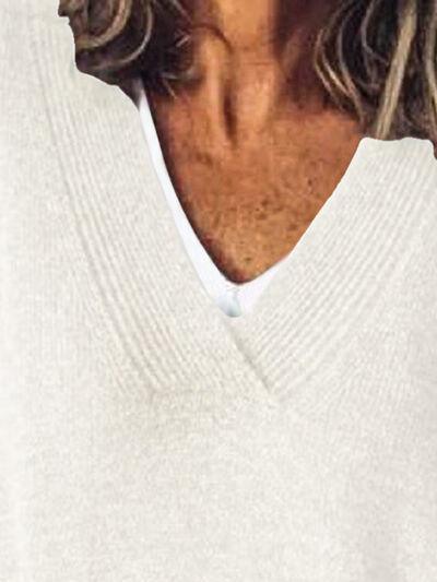 a man with long hair wearing a white sweater