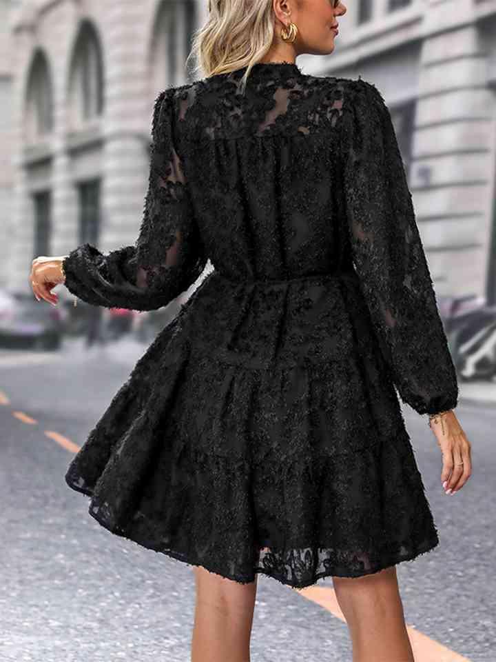 a woman in a black dress is walking down the street