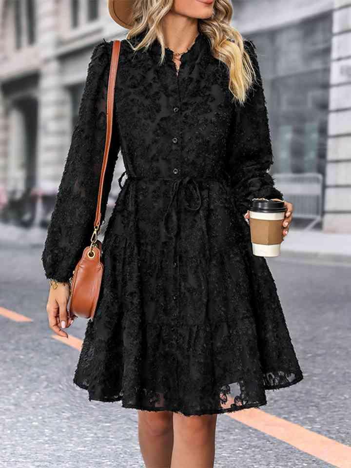 a woman in a black dress and hat walking down the street