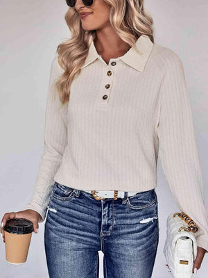 a woman wearing a white sweater and jeans holding a cup of coffee