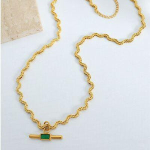 a gold necklace with a green stone on it