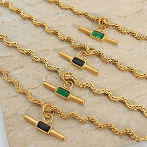 a group of gold chains with green and black stones