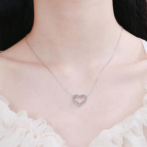 a woman wearing a necklace with a heart on it