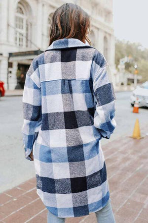 a woman walking down the street wearing a blue and white checkered coat