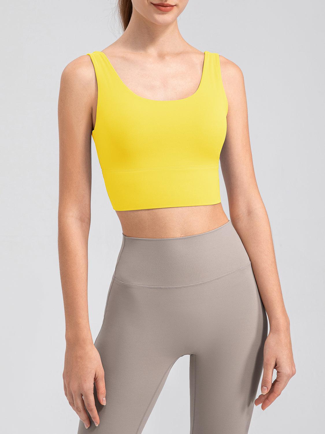 a woman wearing a yellow crop top and grey leggings