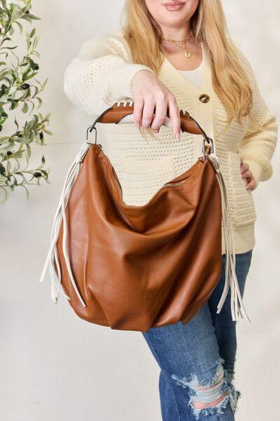 a woman is holding a brown purse