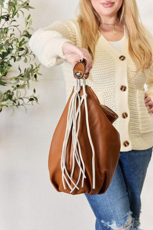 a woman holding a brown purse and a white wall