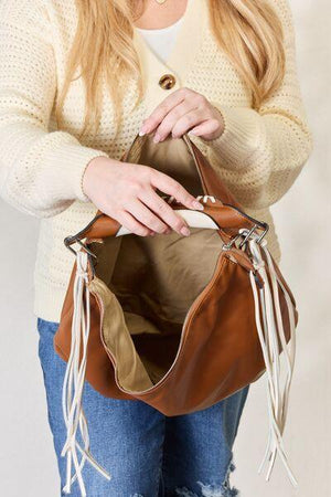 a woman is holding a brown purse