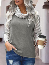 a woman holding a coffee cup and wearing a gray sweater