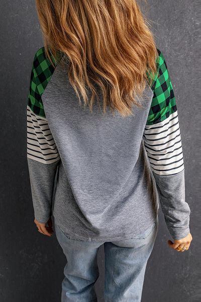 a woman with long hair wearing a gray and green sweater