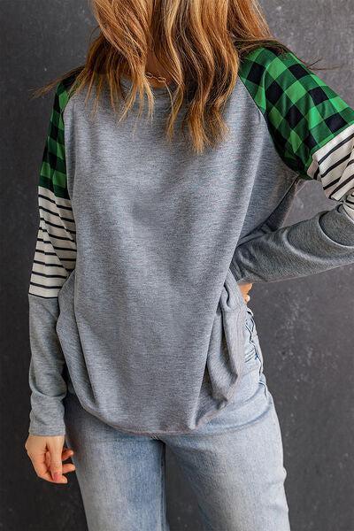 a woman wearing a grey and green sweater and jeans