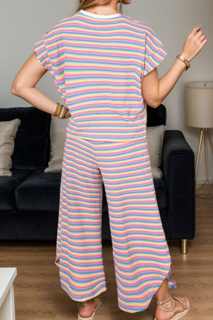 a woman standing in front of a couch wearing a pink and blue striped jumpsuit