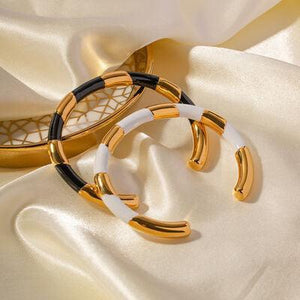 two gold and white bracelets on a white satin