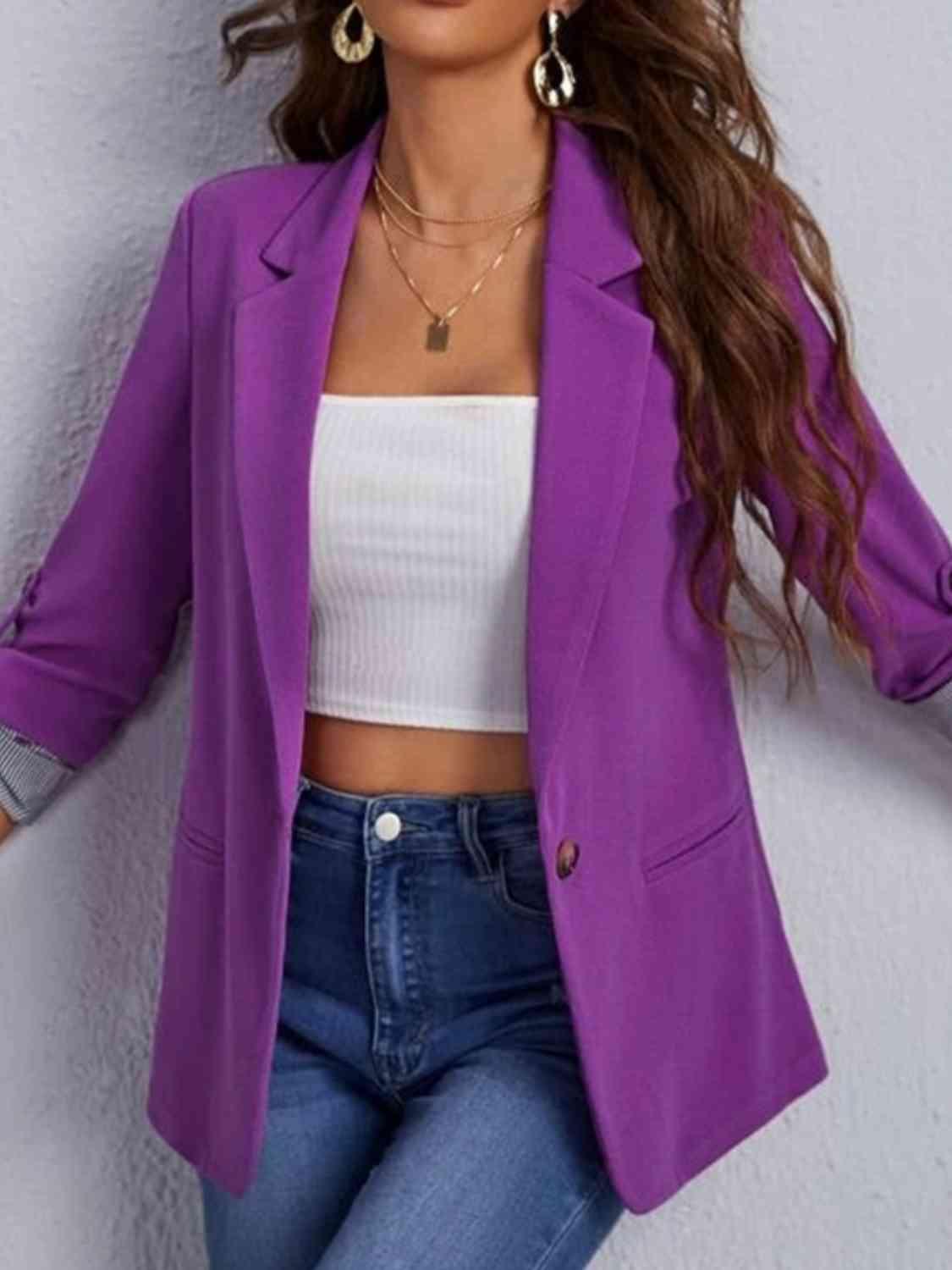 a woman wearing a purple blazer and jeans