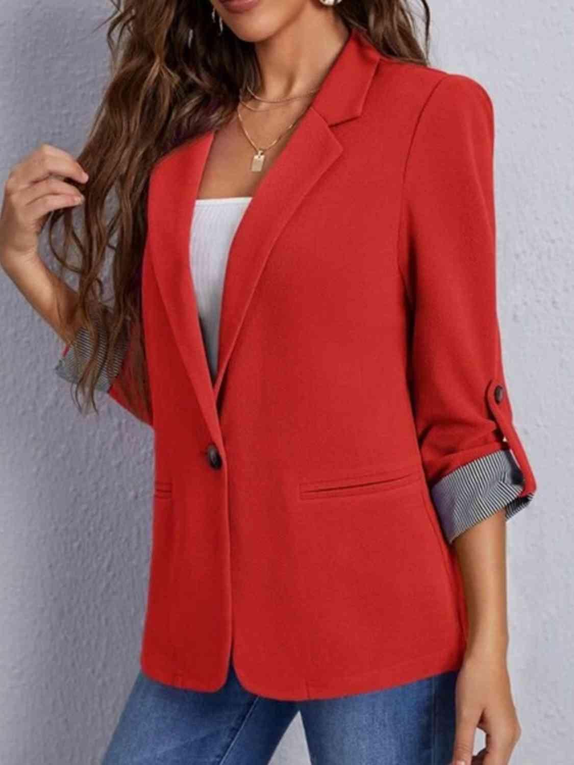 a woman wearing a red blazer and jeans