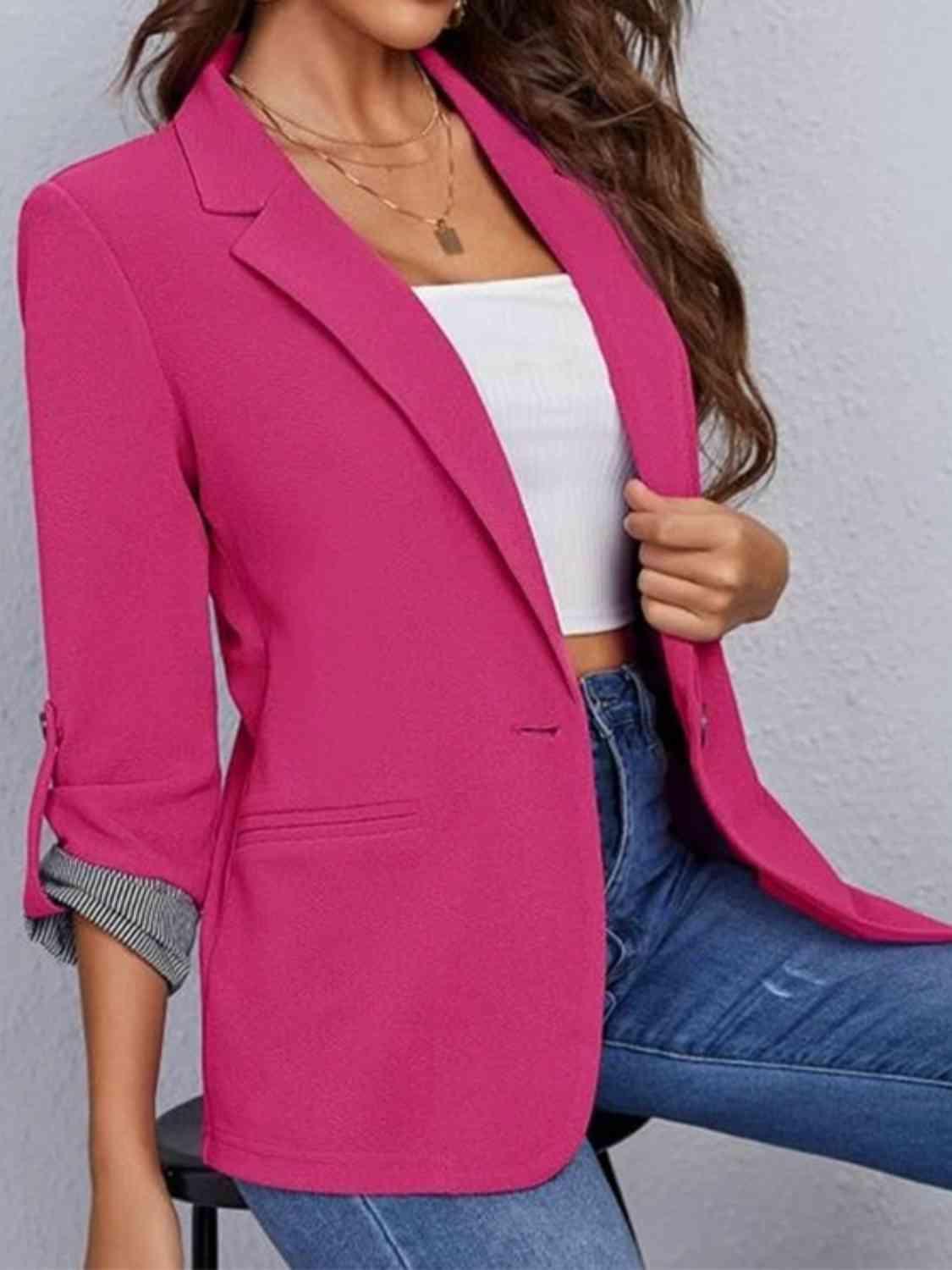 a woman sitting on a chair wearing a pink blazer