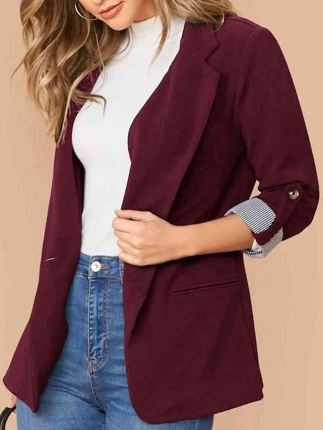 a woman wearing a burgundy blazer and jeans