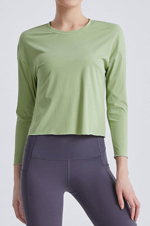 a woman wearing a green top and grey pants