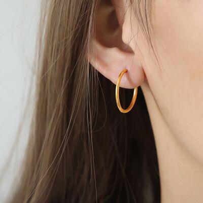 a woman wearing a pair of gold hoop earrings