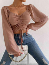 a woman wearing a tan top and jeans