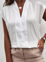 a woman wearing a white blouse and tan pants