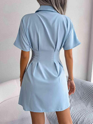 a woman in a blue shirt dress standing on a bed