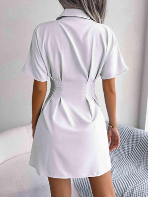 a woman in a white shirt dress standing on a bed