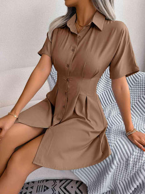 a woman sitting on a bed wearing a brown shirt dress