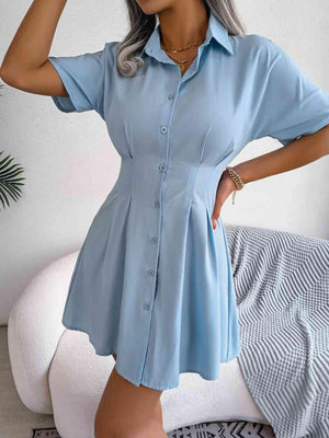 a woman in a blue shirt dress posing for the camera