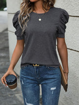 a woman in a gray top and jeans holding a coffee cup