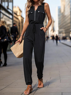 a woman in a black jumpsuit is standing on a sidewalk