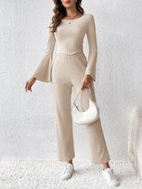 a woman in a beige jumpsuit and white purse