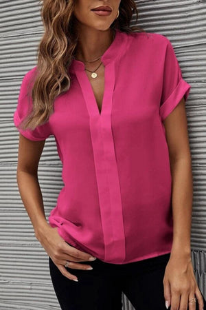 a woman wearing a pink blouse and black pants