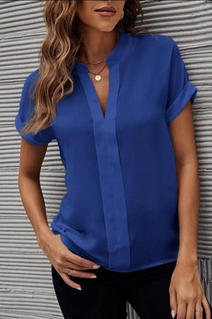a woman wearing a blue blouse and black pants