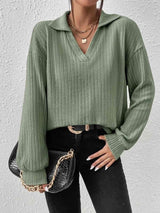 a woman wearing a green sweater and black jeans