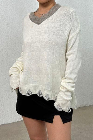a woman wearing a white sweater and black skirt