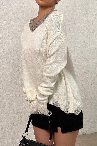 a woman in a white sweater holding a black purse