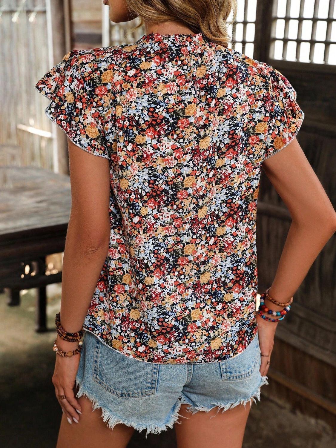 a woman wearing a floral shirt and denim shorts