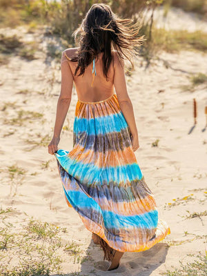 a woman in a colorful dress walking on the beach