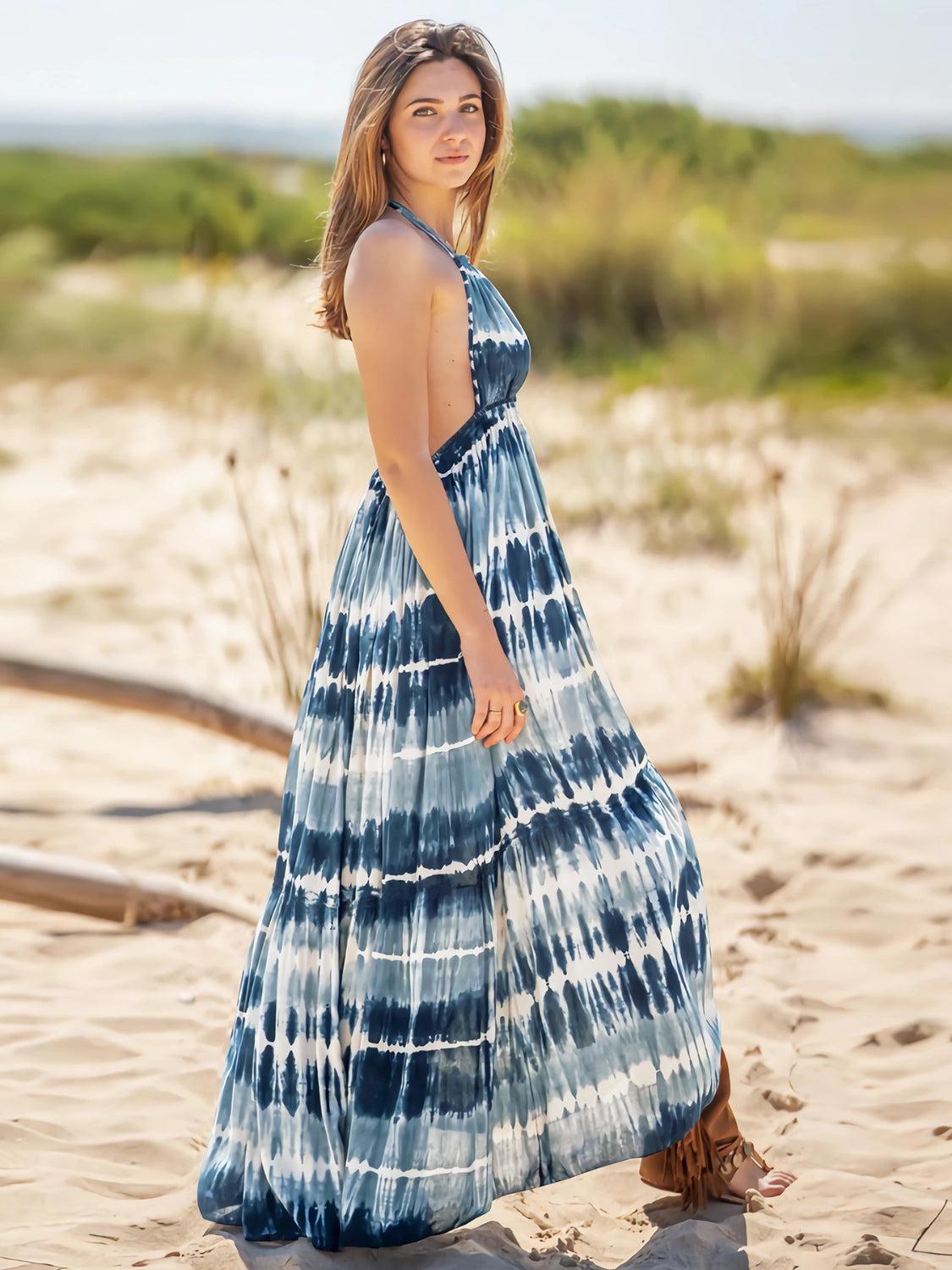 a woman in a blue and white dress standing on a beach